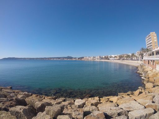 The beautiful beach and buildings by the calm water of the bay captured on a warm sunny day
