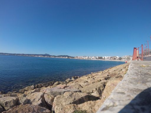 A beautiful view of the pier by the ocean with houses in the background captured on a sunny day