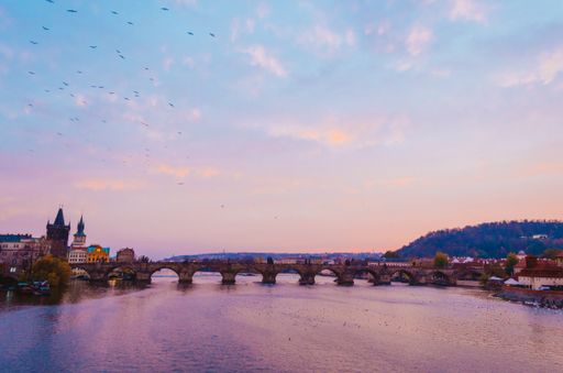 A scenic view of the Vltava river and Charles Bridge in Prague, Czechia in the sunset