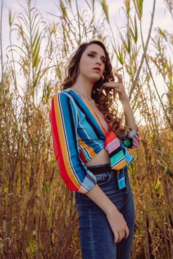 A vertical shot of a female Caucasian wearing a striped blouse and jeans posing on a sunny day