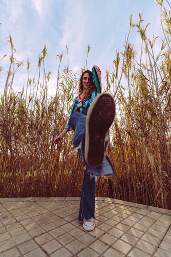 A vertical shot of a female Caucasian wearing a striped blouse and jeans posing on a sunny day