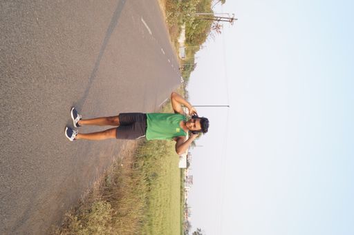 A vertical shot of the young man in a sports outfit training outside.