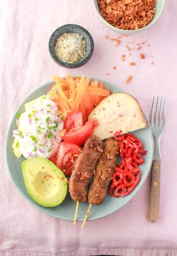 A vertical closeup shot of a lacto-vegetarian dinner in a blue plate on a pink surface