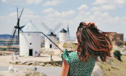 A rear view of a young woman posing against famous old windmills in Consuegra town, Spain
