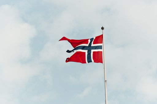 A shot of the flag of Norway against the blue cloudy sky