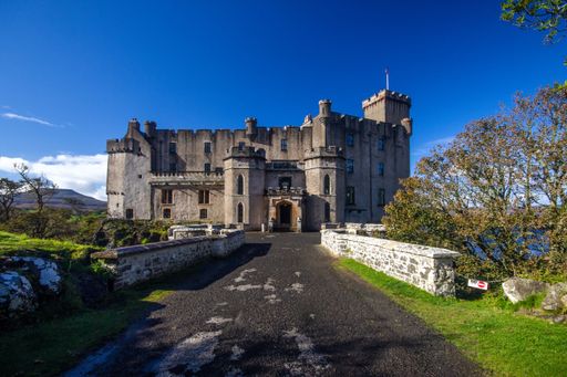 The historical Dunvegan Castle in the Isle of Skye in Scotland with a blue sky in the background