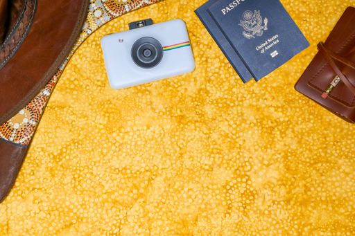 A top view of an American passport and polaroid camera on a yellow background with copy space, traveling concept