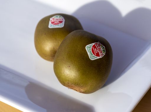 2 whole zespri red kiwi fruit with label on sitting on a white plate