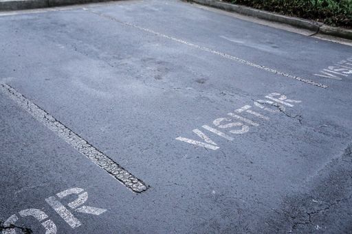 A high angle shot of a parking lot with the text "Visitor" painted on the ground