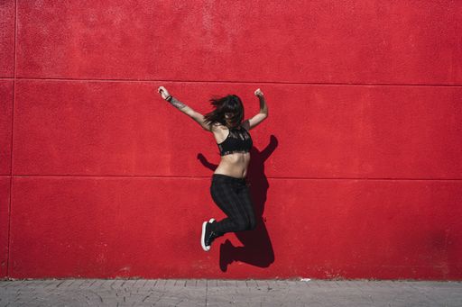 A young attractive Caucasian female with tattoos standing against a red wall