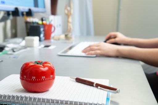 A selective focus shot of an organized desk and a person working on a computer
