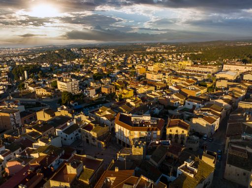 Spectacular aerial view of bright morning sun shining through clouds an illuminating houses on streets of town at sunrise.