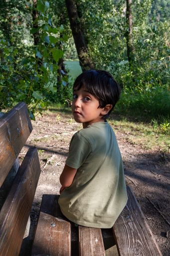 A closeup of a little boy looking from a park bench