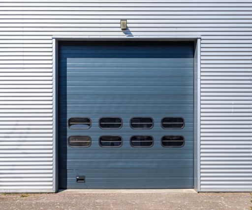 A closeup shot of a blue garage door on a white metal shutter wall during daylight