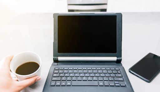 A high angle shot of a person drinking coffee while working on the computer