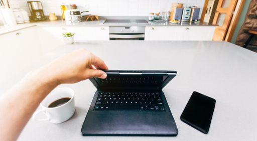 A high angle shot of a person drinking coffee while working on the computer