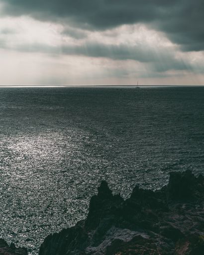 A vertical shot of the Azure Coast with the cliffs by the water under the gloomy sky