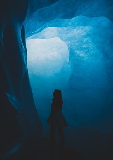 A vertical shot of a female silhouette standing in the Swiss Alps ice cave