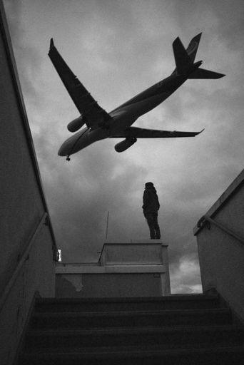 A vertical grayscale shot of an airplane flying over Berlin, Germany