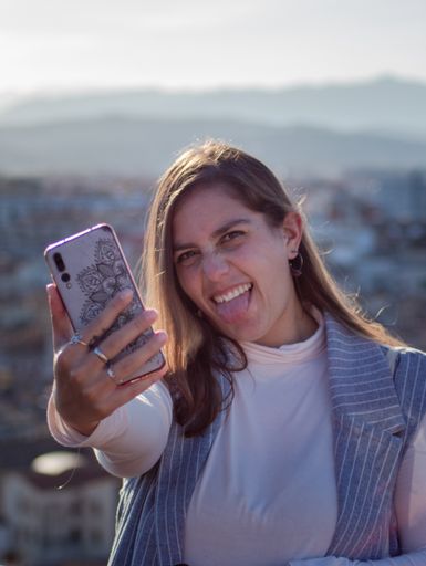 A beautiful Hispanic female with a phone posing for a photo on a sunny day
