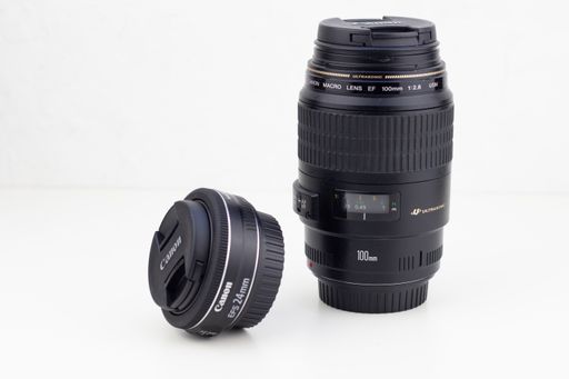 A closeup of 100 mm and 24 mm camera lenses from Canon isolated on a white background