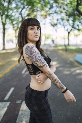 A young attractive Caucasian female with tattoos standing in the park and making a cute face