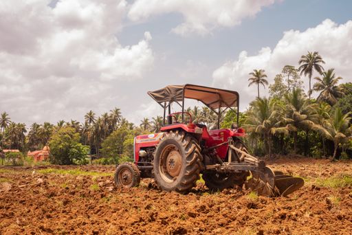 Agricultural Landscape view in Goa/India with tractor in foreground. Farmer cultivating farm land with tractor/machinery.