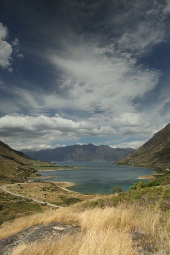 A vertical shot of a lake surrounded by mountains under a cloudy sky