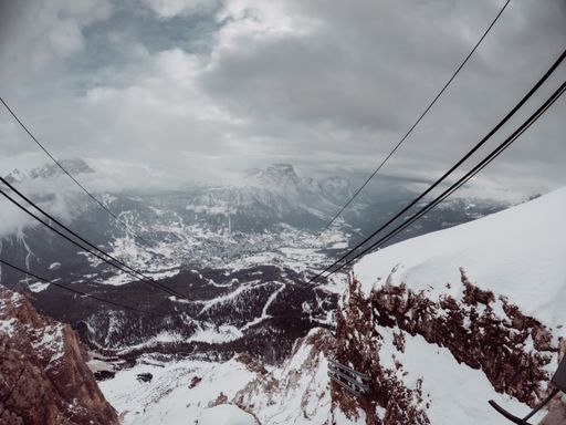 A perspective view from the cable car of mountains covered in snow.