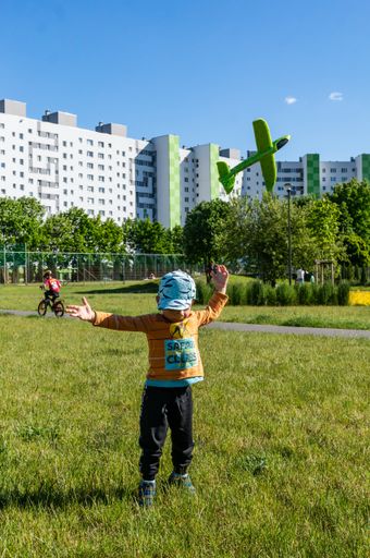 Young small two years old boy throwing a green foam plane at a park in the Orla Bialego area.