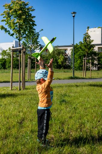 Young small two years old boy throwing a green foam plane at a park in the Orla Bialego area.