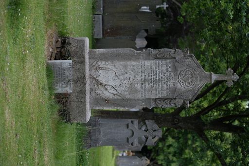 A vertical shot of a gravestone with a cross in a large cemetery in Dublin, Ireland