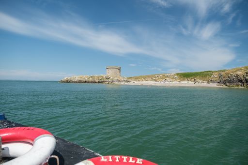 A Martello tower at Irelands Eye island from boat at sunny day near marina