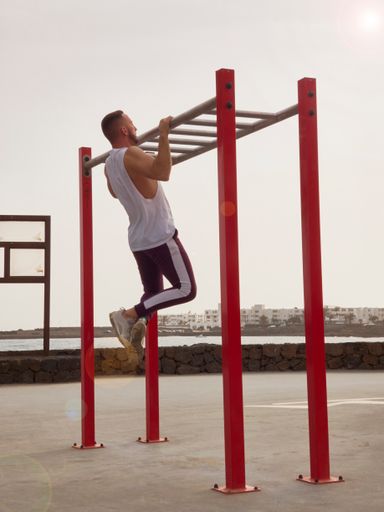 A photo of a man working out on the playground during the daytime
