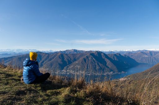A Hispanic man on top of the mountain jumping with joy admiring the landscape of Lago di Como, Italy