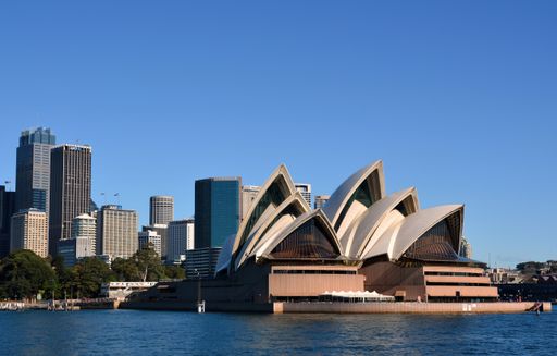 A harbour view of the Opera House and skyscrapers of the central business district on a sunny day in Sydney, Australia.