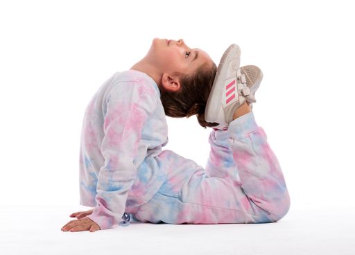 A portrait of a little girl in sportswear doing gymnastics in photo studio on white background