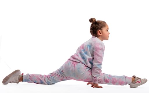 A portrait of a little girl in sportswear doing gymnastics in photo studio on white background