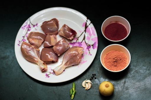A closeup shot of chicken pieces with spices on the side