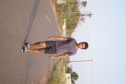 A vertical shot of the young man walking along the road.