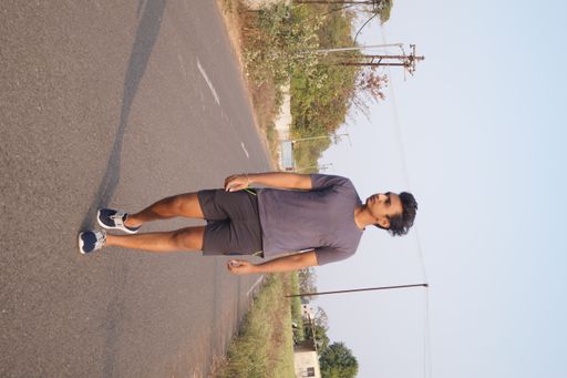 A vertical shot of the young man walking along the road.