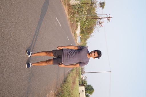 A vertical shot of the young man standing on the road.