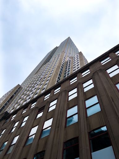 A vertical low angle shot of a tall building on the clouds background