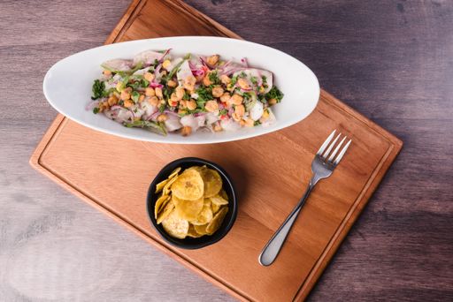 A high angle shot of a bowl of homemade food with vegetables and a bowl of homemade chips on a table