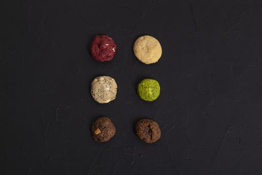 A high angle shot of six different cookies on a black rough surface