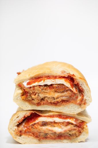 A vertical closeup of a delicious sandwich cut into two pieces isolated on white background.