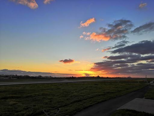 A distant view of the sunset with fields and roads on the foreground
