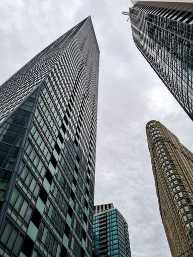 A vertical low angle view of tall office towers against the cloudy sky