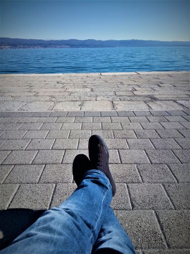A vertical shot of a man resting outdoor near the coast