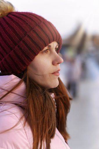 A vertical closeup shot of the Caucasian female looking away on the blurry background
